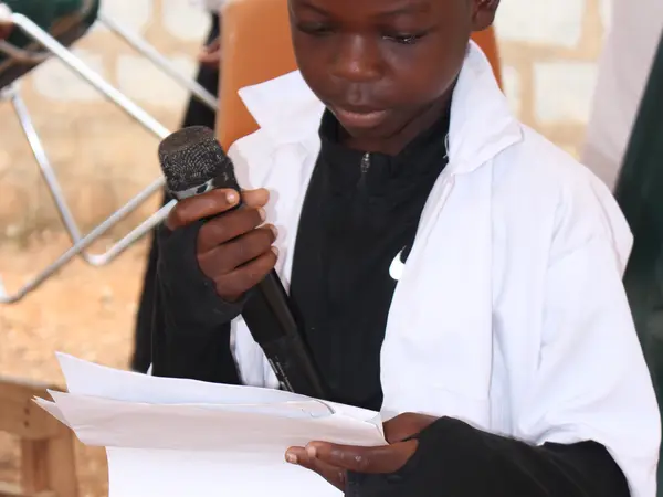 A HEWIS pupil reading aloud into a microphone at a school event